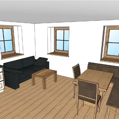 Ein einfaches Wohnzimmer mit einem schwarzen Sofa, einem Tisch und Stühlen. Es hat zwei Fenster, die viel Licht hereinlassen.