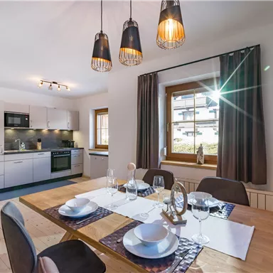 A modern kitchen with an inviting dining area. Large windows provide plenty of light and a cozy atmosphere.