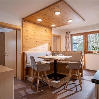 A cozy kitchen with a dining area and modern furniture. Plenty of daylight streams through the windows, creating an inviting atmosphere.