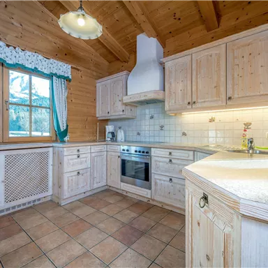 Eine gemütliche Holzküche mit modernen Geräten. Große Fenster bieten einen Blick auf die Natur.