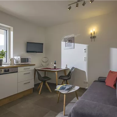 A modern and bright apartment with a small kitchen and a cozy living area. The space is cheerfully furnished and has a beautiful view.