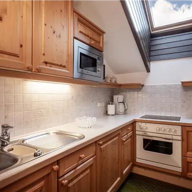 A cozy kitchenette with wooden cabinets and modern appliances. A skylight provides plenty of daylight.