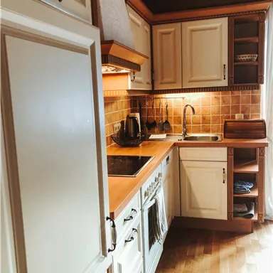 Eine moderne Küche mit hellen Schränken und Holzoberflächen. Die Einrichtung ist funktional und einladend.