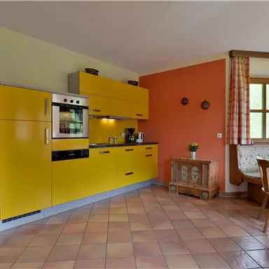 Eine moderne Küche mit gelben Schränken und einem gemütlichen Essbereich. Die Wände sind in harmonischen Farben gehalten und das Licht strömt durch die Fenster.