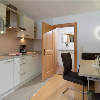 A modern kitchen with elegant furniture and a dining area. The door is open and there is a cozy atmosphere.