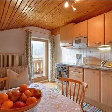 Eine gemütliche Küche mit Holzdecke und modernen Geräten. Auf dem Tisch steht eine Schüssel mit Äpfeln.