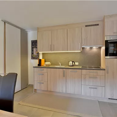 A modern kitchen with light wooden cabinets and an elegant countertop. It is well equipped with high-quality appliances and offers an inviting space for cooking.