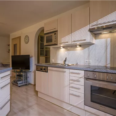 Eine moderne Küche mit hellen Holzmöbeln und ausreichendem Platz. Die Geräte sind in einem eleganten Design integriert.