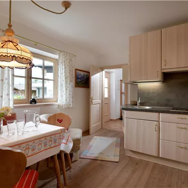A bright kitchen with wooden cabinets and a small dining area. The space is designed to be friendly and welcoming.