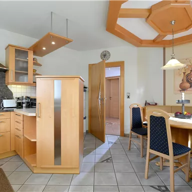 Eine moderne Küche mit Holzmöbeln und einer gemütlichen Essecke. Der Raum ist hell und gut strukturiert.