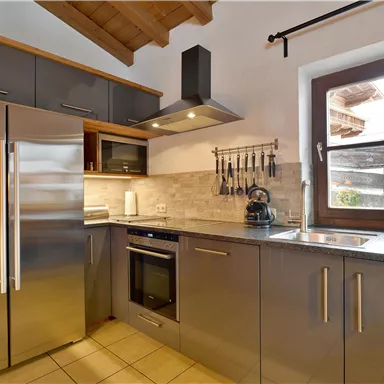 Eine moderne Küche mit Edelstahlgeräten und eleganten Oberflächen. Das Fenster bietet einen Blick nach draußen und lässt viel Licht herein.