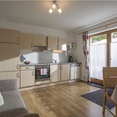 Eine helle Küche mit modernen Geräten und Holzfußboden. Das Zimmer hat einen gemütlichen Essbereich und große Fenster mit Blick nach draußen.