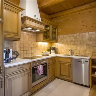 Eine gemütliche Küche mit Holzschränken und moderner Ausstattung. Der Raum hat eine warme, einladende Atmosphäre.