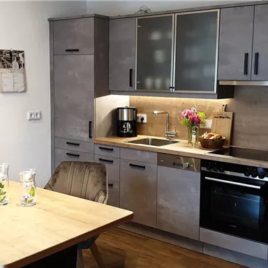 Eine moderne Küche mit einem Esstisch und Stühlen. Die Küchenzeile ist hell und gut ausgestattet.