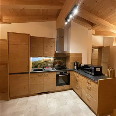 Eine moderne Küche mit Holzschränken und einer schwarzen Arbeitsplatte. Die Atmosphäre ist hell und einladend.