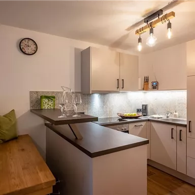 A modern kitchen with bright cabinets and a wood worktop. The lighting is atmospheric and there are some decorative elements.