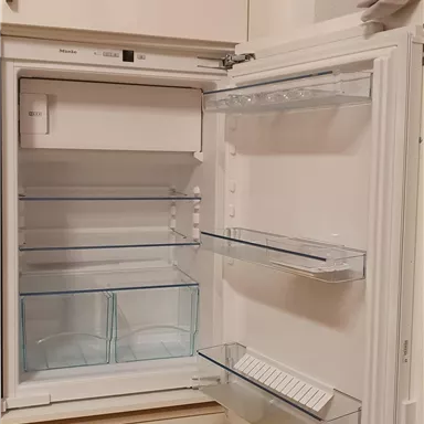 An open refrigerator with clear compartments and shelves. It is empty inside and has no food.