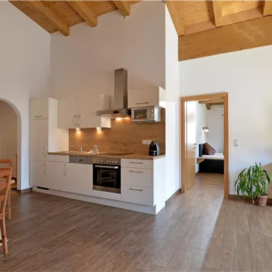 Eine moderne Wohnung mit einer hellen Küche und einem gemütlichen Essbereich. Der Holzboden und die Holzdecken verleihen eine warme Atmosphäre.