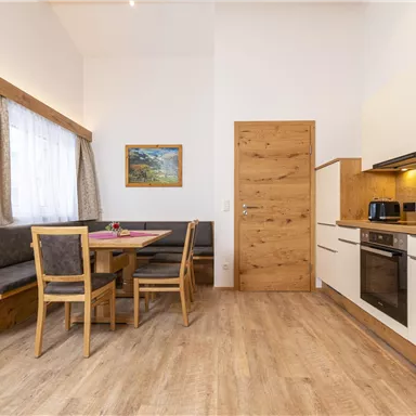 Eine moderne Küche mit einem Esstisch und Holzbank. Hell erleuchtet, mit einem praktischen Design und gemütlicher Atmosphäre.