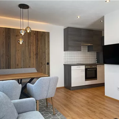 A modern kitchen-living room with wooden details. The space is bright and inviting, with a cozy seating area.
