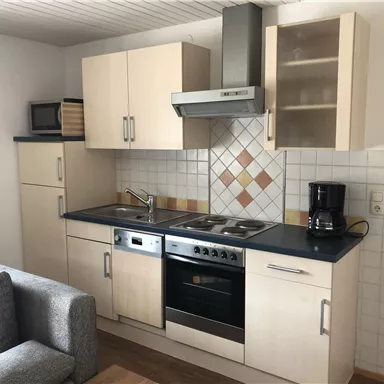 Eine moderne Küchenzeile mit hellen Schränken und Küchenutensilien. Der Bereich ist sauber und gut organisiert.