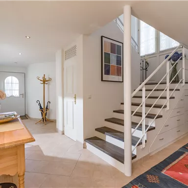 A bright entrance area with a staircase and a cozy atmosphere. The furniture is modern and functional, ideal for an inviting space.