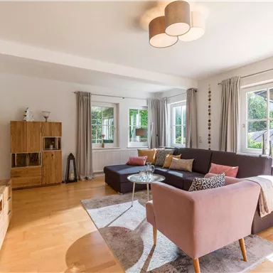 A modern living room with a cozy sofa and a table. Large windows let in plenty of daylight.