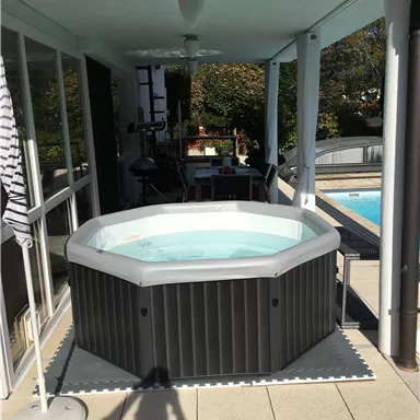 A hot tub on a terrace overlooking a pool. The area is bright and invites relaxation.
