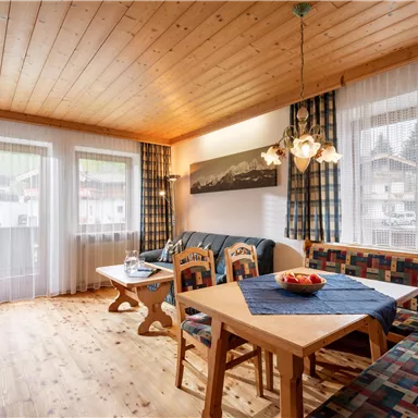 A cozy living area with wooden floors and large windows. A seating group and a table invite you to relax and linger.