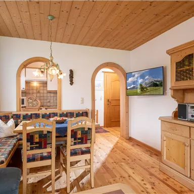 A cozy living space with a dining area and wooden paneling. The walls are light, and the ambiance feels friendly and inviting.