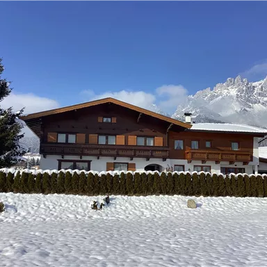 A charming house covered in snow in winter. Majestic mountains can be seen in the background.