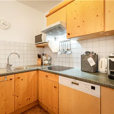 Eine gemütliche Küche mit Holzmöbeln und modernen Geräten. Die Arbeitsfläche ist übersichtlich und gut organisiert.