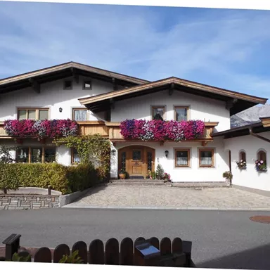 A beautiful country house with colorful flower boxes at the windows. The well-kept garden and the stony driveway give the house an inviting character.