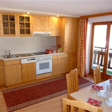 A cozy kitchen with wooden cabinets and modern appliances. The dining area is bright and welcoming, featuring a table and chairs.