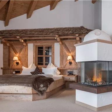 Ein gemütliches Schlafzimmer mit einem modernen Kamin und natürlichem Holzdesign. Das Zimmer strahlt eine warme und einladende Atmosphäre aus.