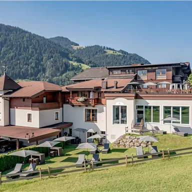 Ein modernes Hotel inmitten von grünen Hügeln und Bergen. Die Umgebung ist ruhig und einladend, ideal für Erholung und Naturgenuss.