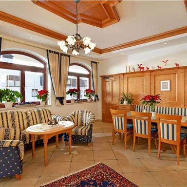 A cozy lounge with blue-and-white striped sofas and a wooden table. Large windows let in plenty of natural light.