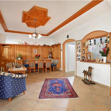 An inviting reception area with wooden furniture and a cozy armchair. Pictures and souvenirs hang on the wall, and a carpet complements the decor.