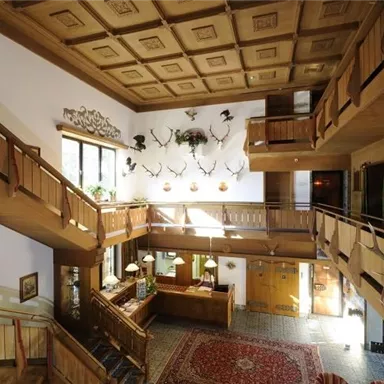 Ein einladender Empfangsbereich mit Holzverkleidung und dekorativen Jagdtrophäen. Große Fenster lassen viel Licht herein und sorgen für eine freundliche Atmosphäre.