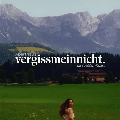 A beautiful old building amid a picturesque mountain landscape. In the foreground stands a woman in a long dress.