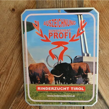 A sign with the inscription "AWARD MANAGEMENT PROFESSIONAL" and images of cows. It represents cattle breeding in Tyrol.