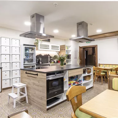 Eine moderne Küche mit Holzdetails und einer großen Kochinsel. Es gibt einen Essbereich mit bequemen Bänken und Tischen.