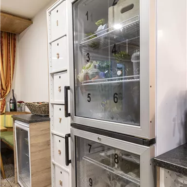 Ein Kühlschrank mit durchsichtigem Türdesign, der verschiedene Lebensmittel und Getränke zeigt. Daneben steht ein weiterer kleiner Kühlschrank.