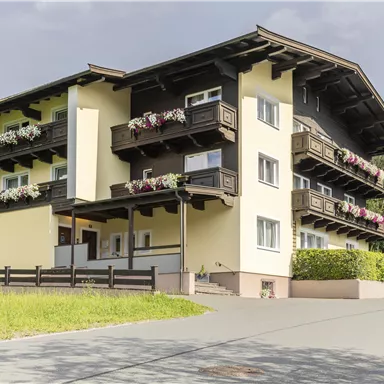 Ein modernes Gebäude mit mehreren Etagen und einem Balkon. Blick auf eine ruhige Straße mit Grünflächen.