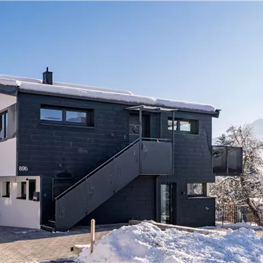 Ein modernes Haus in schneebedeckter Umgebung. Klare Linien und große Fenster bieten einen schönen Ausblick auf die Winterlandschaft.