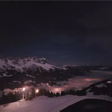 Eine spektakuläre Berglandschaft unter dem Nachthimmel. Sanfte Lichter und Nebel verleihen der Szene eine mystische Atmosphäre.