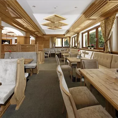 An inviting restaurant with warm wooden furniture and cozy seating. Large windows let in plenty of daylight and offer a view of nature.