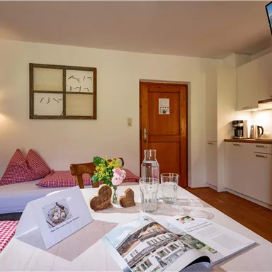 Ein gemütlicher Wohnraum mit einem Esstisch, einer kleinen Küche und einem modernen Fernseher. Die Dekoration ist einladend und bietet eine entspannte Atmosphäre.