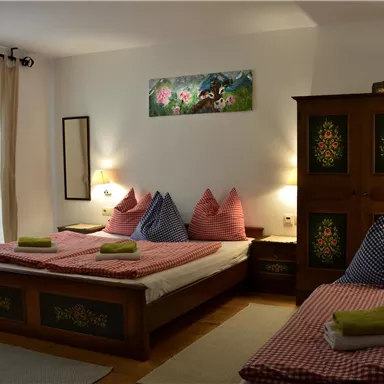 Ein gemütliches Schlafzimmer mit zwei Betten und bunten Kissen. Der Raum ist hell und freundlich mit dekorativen Möbeln.