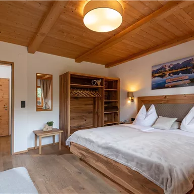 Ein gemütliches Schlafzimmer mit Holzdecke und einem großen Bett. Die Wände sind hell, und es gibt viel natürliches Licht.